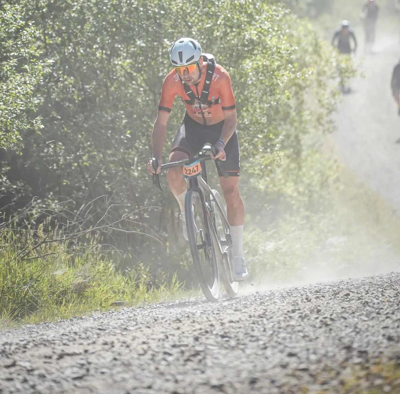 Corredor de gravel en carrera por una pista de tierra levantando polvo
